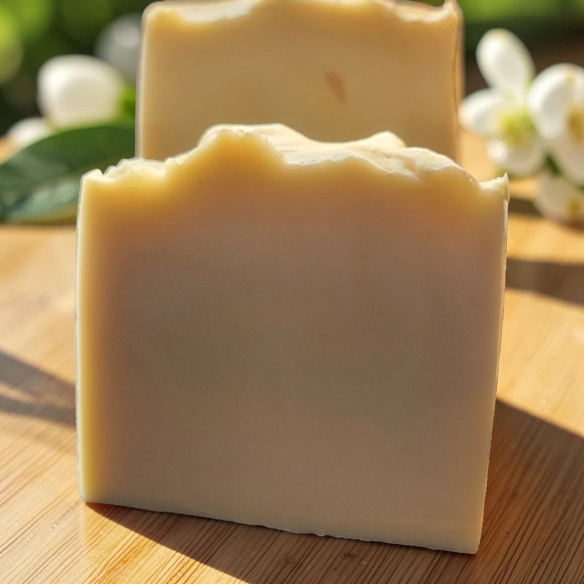 Guava Sunshine soap bars on wooden board with white flowers and green leaves